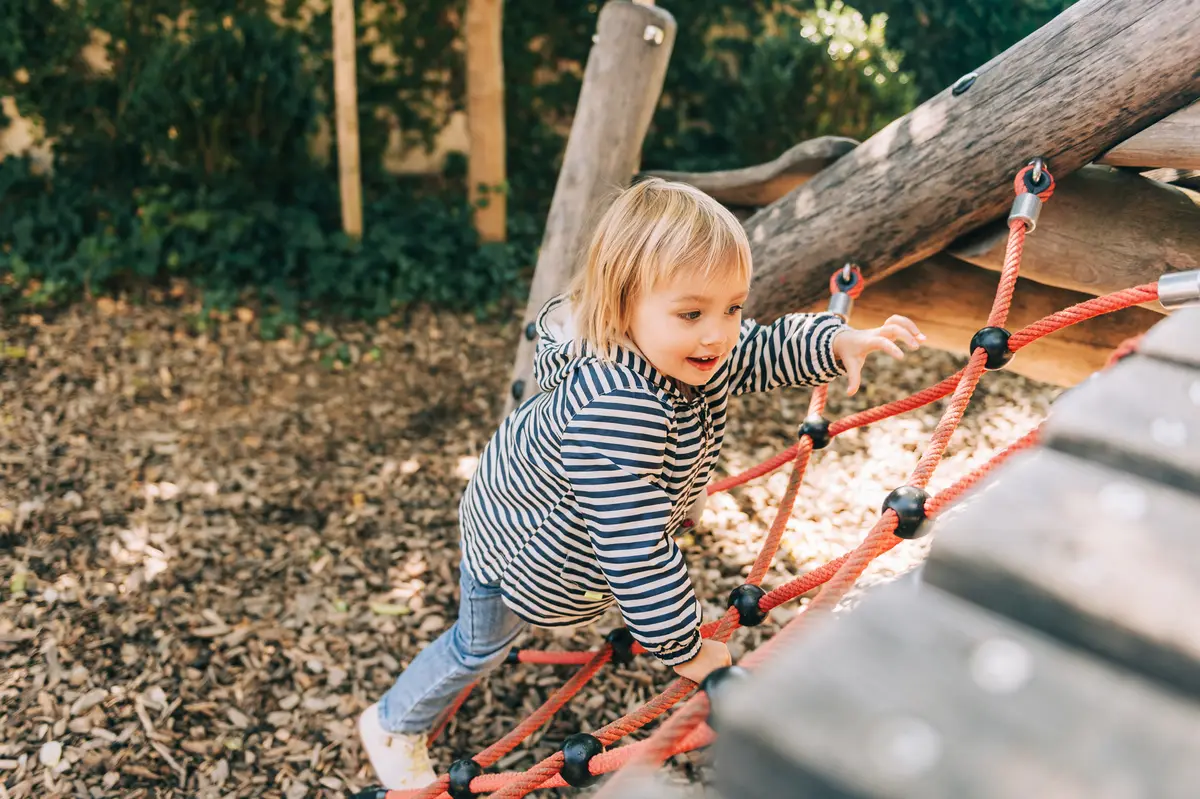 Kind klettert auf einem Spielplatz aus Holz
